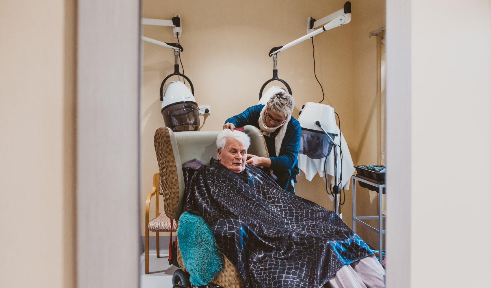 A male resident at Karina Nursing Home receives a hair cut from a hairdresser. 