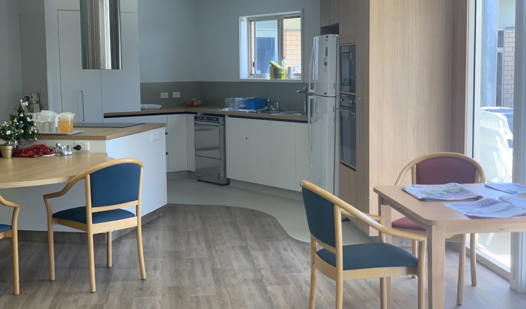 Modern light and airy communal kitchen space with tables and chairs. 